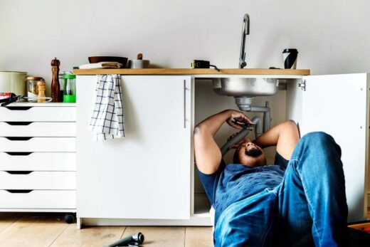 Plombier allongé sous un évier de cuisine