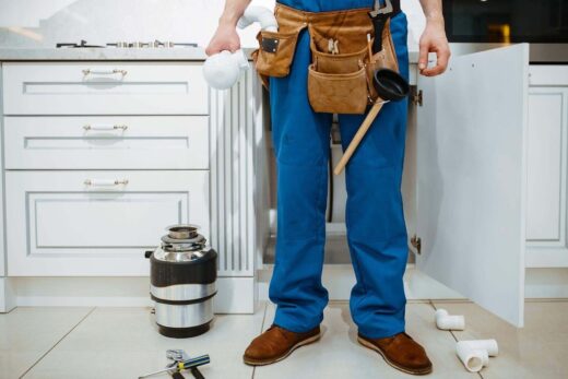 Plombier avec sa ceinture à outils devant un évier